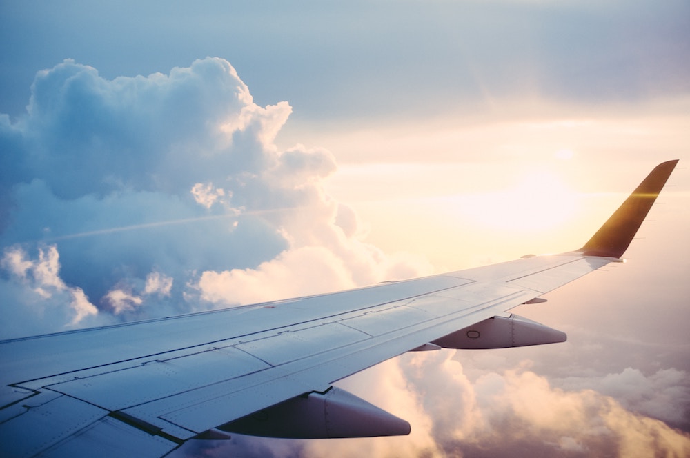 Airplane wing in sky during flight shown surrounded by clouds.