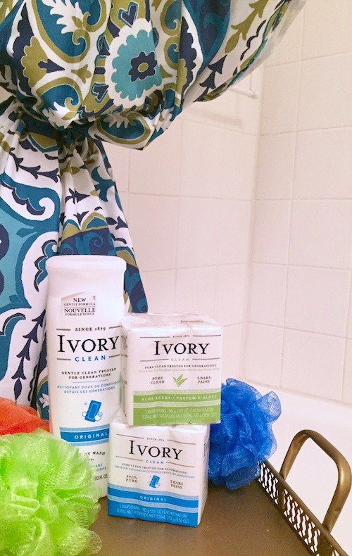 Shown: Open multi-colored shower curtain, Ivory bar soap and Ivory body wash with three bath sponges, in front of a white bath tub. 