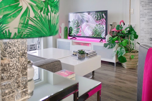 Shown: Living room with white furniture and potted plants. Flat screen television on a white entertainment unit.