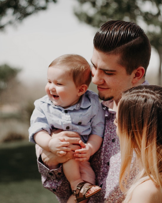 Father holding baby. Mother looking at baby and father.